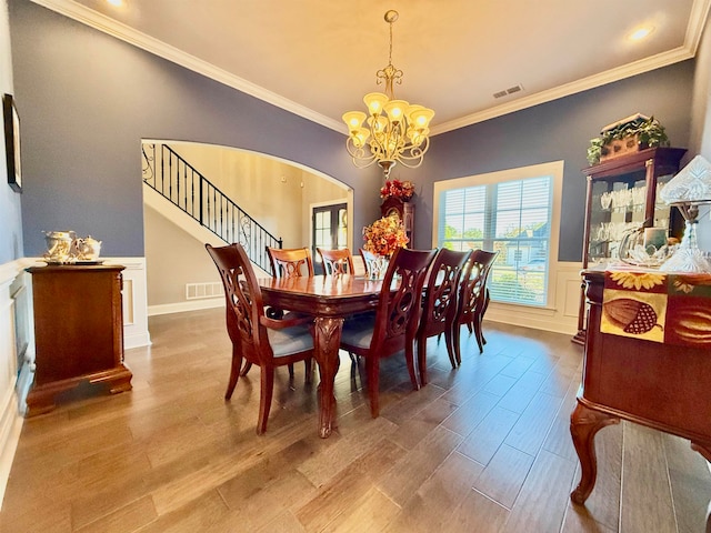 dining room featuring ornamental molding, light wood-type flooring, and a notable chandelier