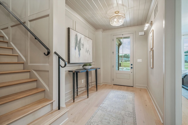 foyer entrance featuring light hardwood / wood-style floors, wood ceiling, and crown molding