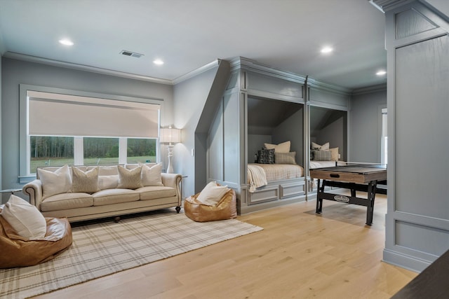 sitting room with ornamental molding and light hardwood / wood-style flooring