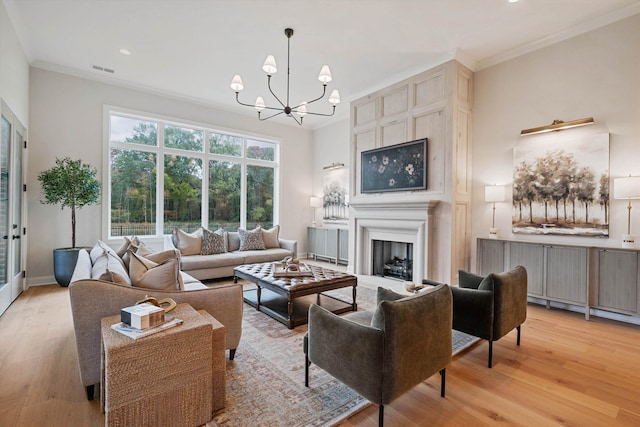 living room with light wood-type flooring, crown molding, and a notable chandelier