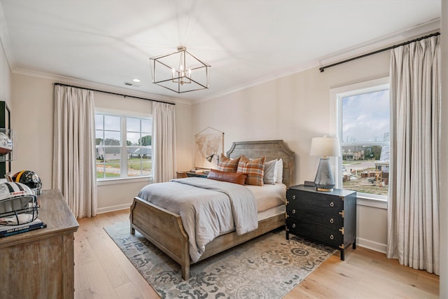 bedroom featuring an inviting chandelier, light hardwood / wood-style flooring, and multiple windows