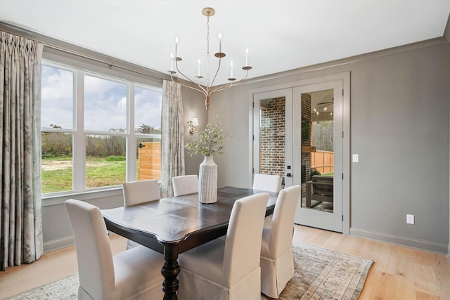 dining space featuring a wealth of natural light, light hardwood / wood-style flooring, french doors, and an inviting chandelier