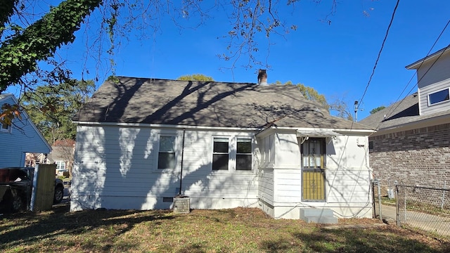 rear view of property featuring cooling unit and a lawn