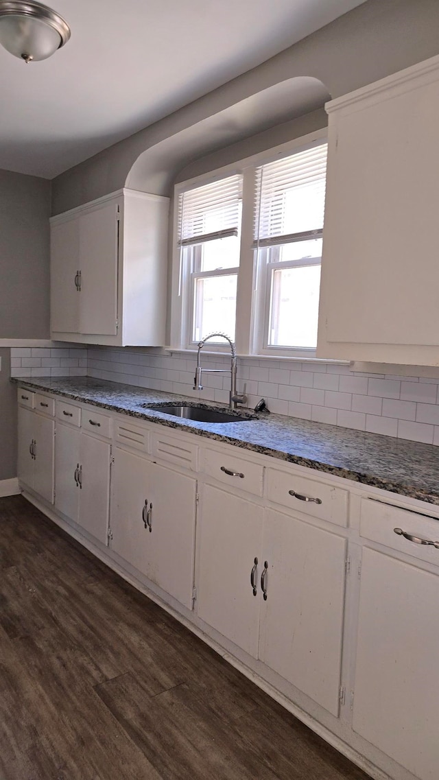 kitchen with dark hardwood / wood-style flooring, decorative backsplash, sink, and white cabinets