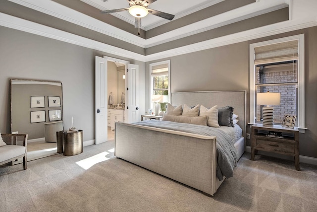 carpeted bedroom featuring ceiling fan, crown molding, a tray ceiling, and ensuite bath