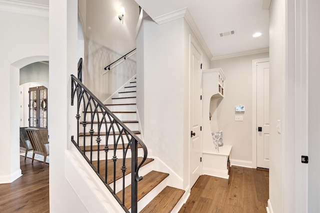 staircase featuring ornamental molding and hardwood / wood-style flooring