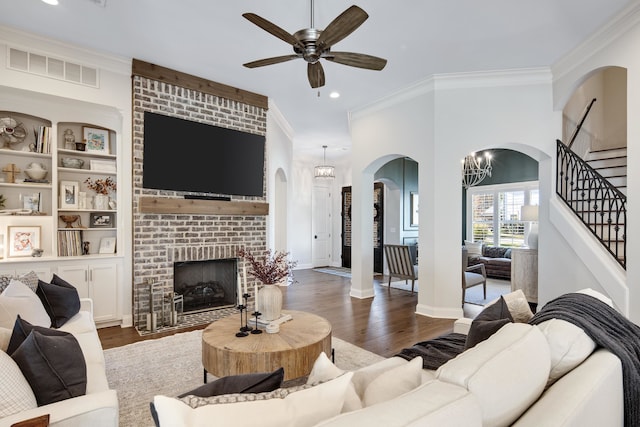 living room with a fireplace, ceiling fan with notable chandelier, dark hardwood / wood-style floors, and ornamental molding