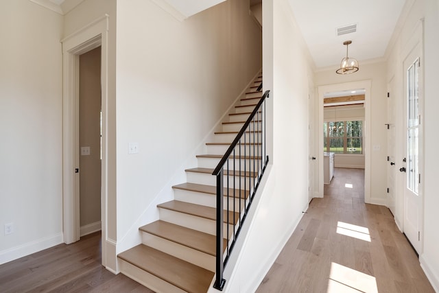 interior space with a notable chandelier, crown molding, and light hardwood / wood-style flooring