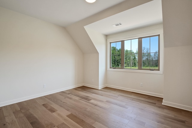 bonus room with light wood-type flooring and lofted ceiling