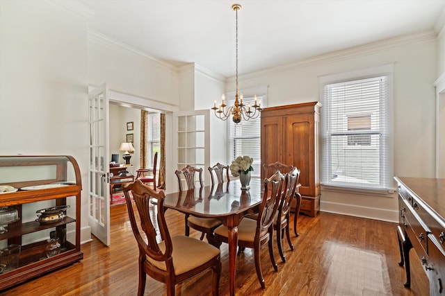 dining room featuring ornamental molding, french doors, dark wood-type flooring, and a notable chandelier