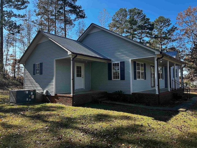 view of front of house featuring covered porch, central air condition unit, and a front yard