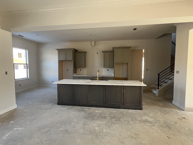 kitchen featuring a center island with sink, ornamental molding, gray cabinetry, and sink