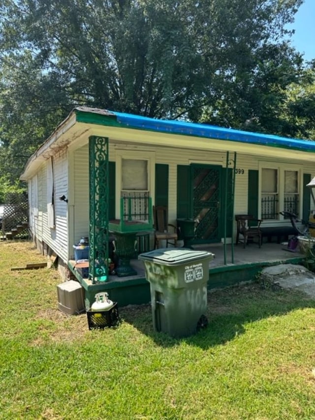 rear view of house with covered porch and a yard