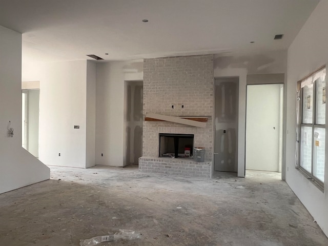 unfurnished living room with a brick fireplace and visible vents