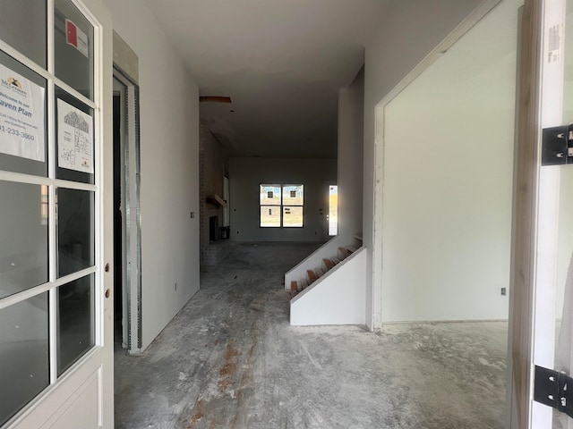 hallway with stairway and unfinished concrete floors