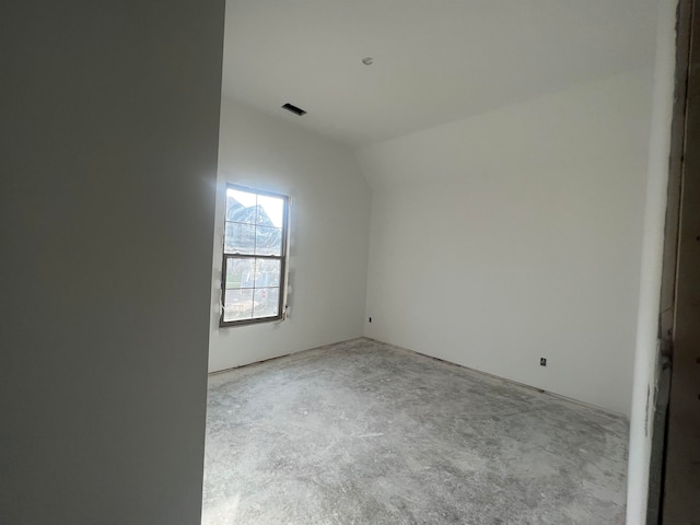 spare room with lofted ceiling and concrete flooring