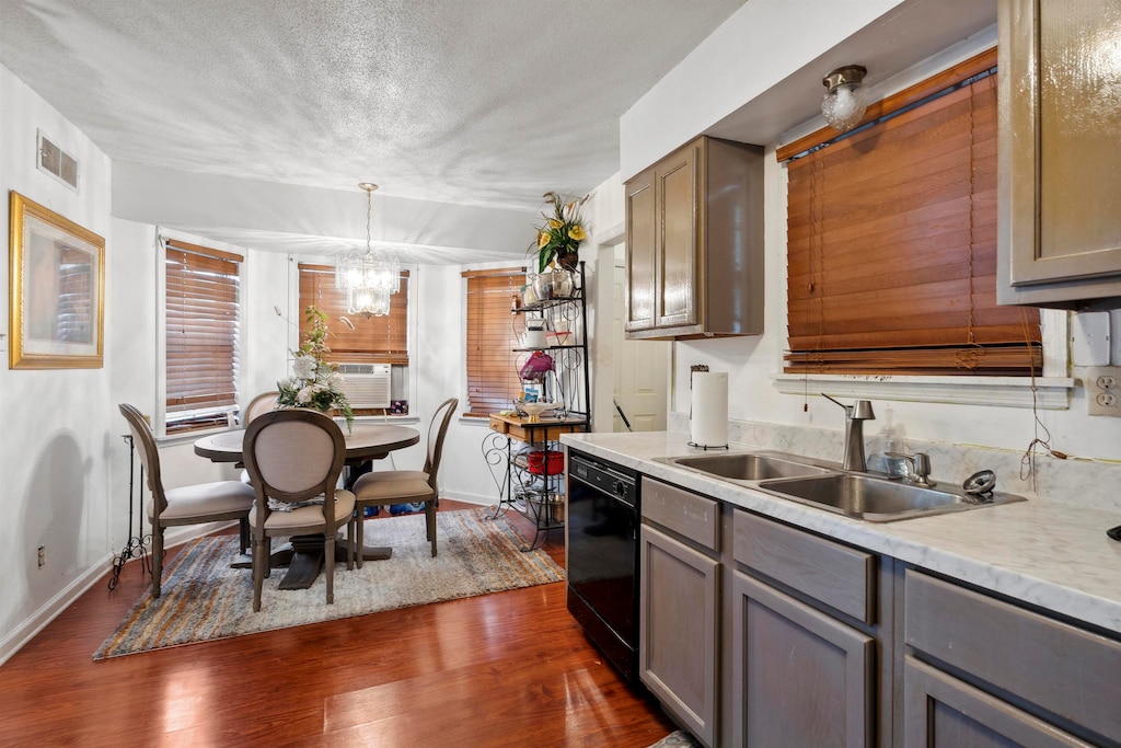 kitchen with a textured ceiling, dark wood-type flooring, sink, decorative light fixtures, and black dishwasher