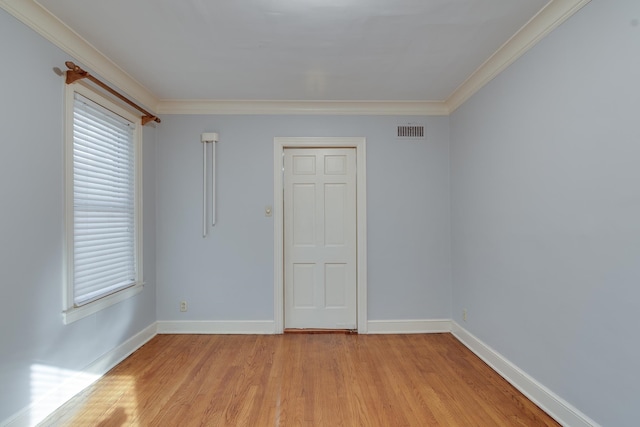 empty room with ornamental molding and light wood-type flooring