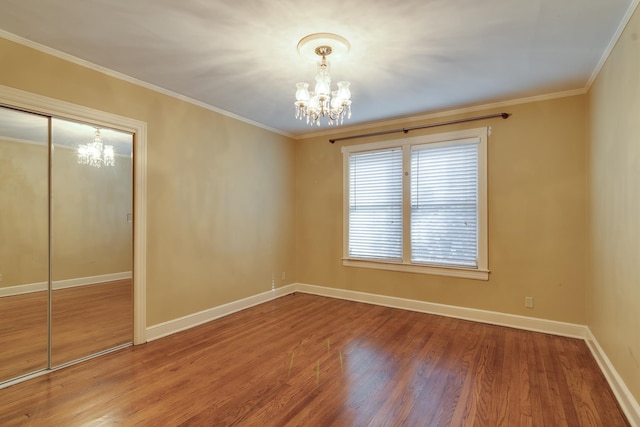 unfurnished room featuring a notable chandelier, wood-type flooring, and crown molding