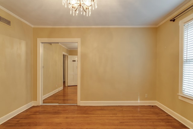 unfurnished room with ornamental molding, a chandelier, and hardwood / wood-style flooring