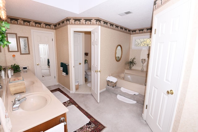 bathroom with vanity, toilet, a textured ceiling, and a washtub