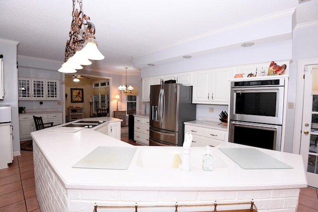 kitchen with appliances with stainless steel finishes, ceiling fan with notable chandelier, light tile patterned floors, decorative light fixtures, and a large island