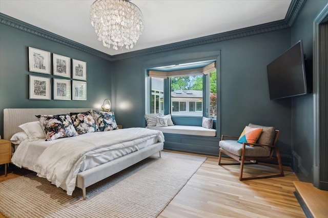 bedroom with a notable chandelier, light hardwood / wood-style floors, and ornamental molding