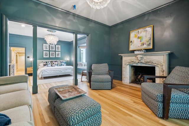 bedroom with a premium fireplace, crown molding, wood-type flooring, and an inviting chandelier