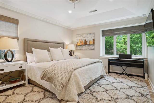 bedroom featuring ceiling fan, a raised ceiling, crown molding, and light hardwood / wood-style flooring