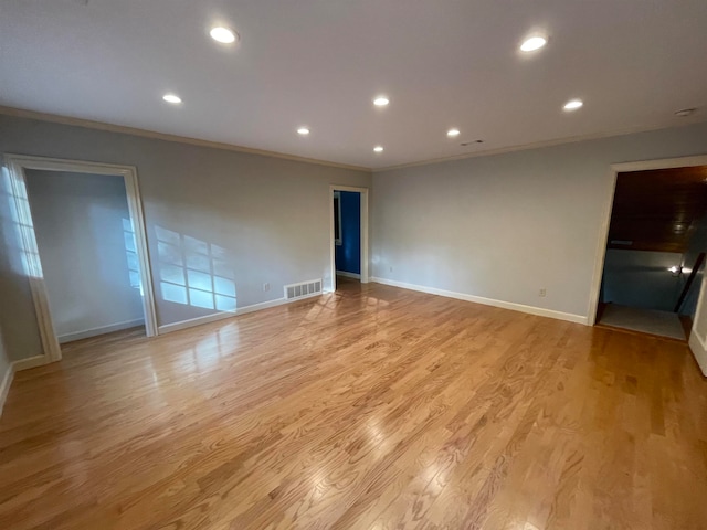 spare room featuring light wood-type flooring and crown molding