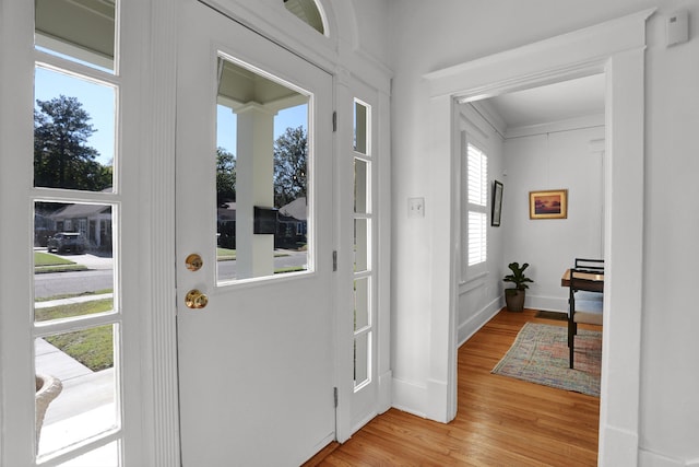 foyer with ornamental molding and light wood-type flooring