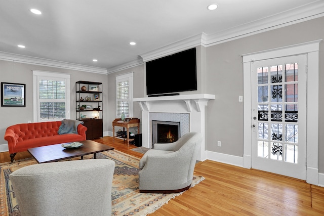 living room featuring a tiled fireplace, crown molding, and hardwood / wood-style flooring