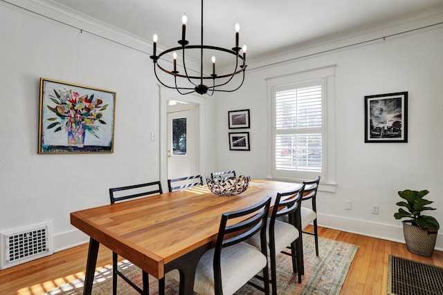 dining space with crown molding, light hardwood / wood-style floors, and a notable chandelier