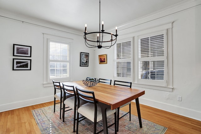 dining area featuring a notable chandelier, ornamental molding, and light hardwood / wood-style flooring