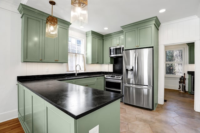 kitchen with kitchen peninsula, stainless steel appliances, sink, pendant lighting, and green cabinets