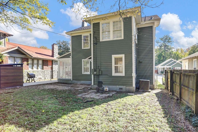 rear view of house featuring a lawn and central air condition unit