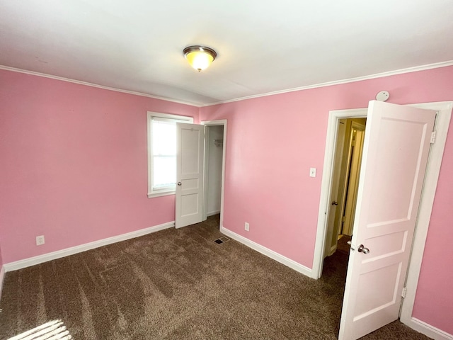 unfurnished bedroom with dark colored carpet and crown molding