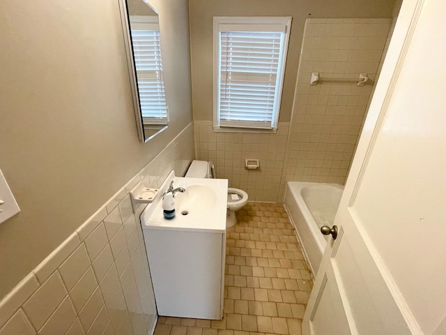 bathroom with tile patterned floors, vanity, a bathtub, and tile walls