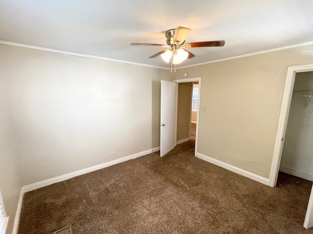 unfurnished bedroom with a closet, dark carpet, ceiling fan, and crown molding