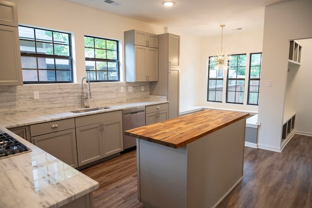 kitchen with a center island, sink, hanging light fixtures, butcher block counters, and stainless steel appliances