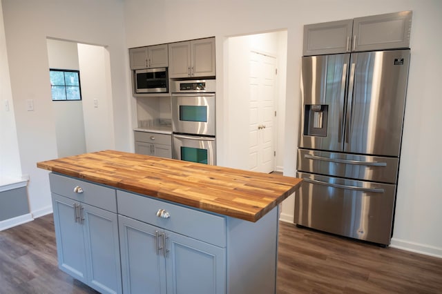 kitchen with a center island, wooden counters, gray cabinets, dark hardwood / wood-style flooring, and stainless steel appliances