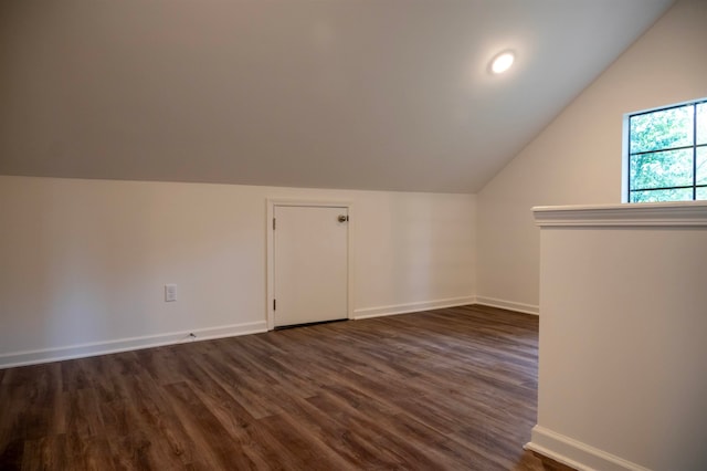 additional living space featuring dark wood-type flooring and vaulted ceiling