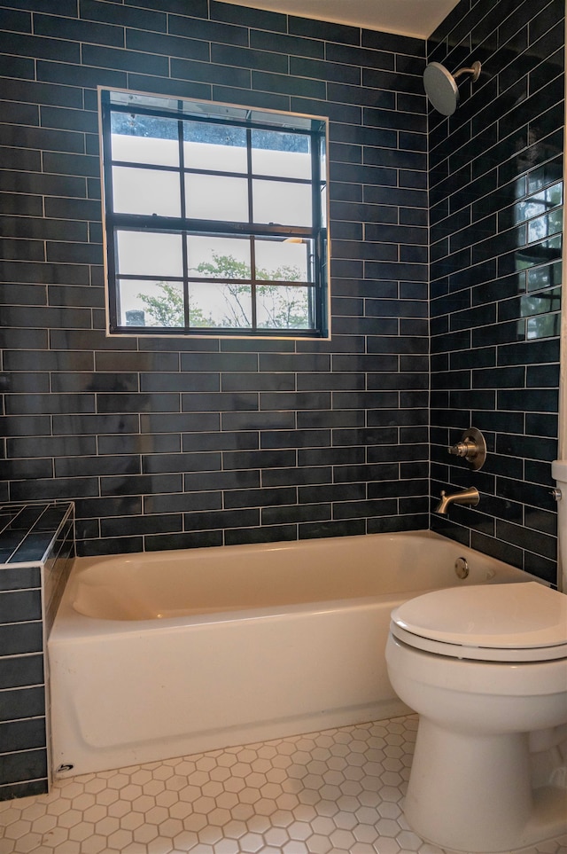 bathroom featuring tile patterned floors, toilet, tiled shower / bath, and a healthy amount of sunlight