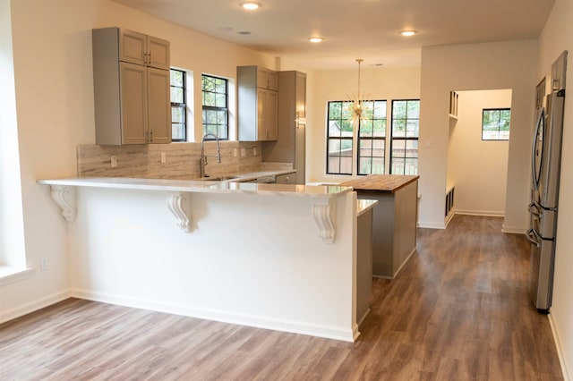 kitchen with dark wood-type flooring, sink, decorative light fixtures, a kitchen bar, and kitchen peninsula