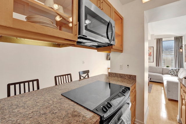 kitchen featuring a breakfast bar area, light hardwood / wood-style flooring, and stove