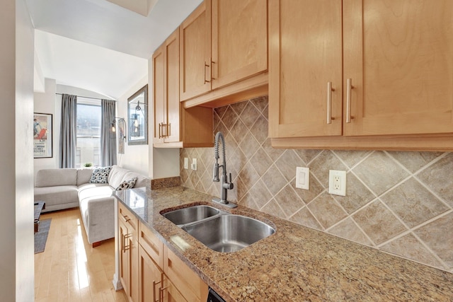 kitchen with light brown cabinets, sink, light stone counters, light hardwood / wood-style flooring, and vaulted ceiling