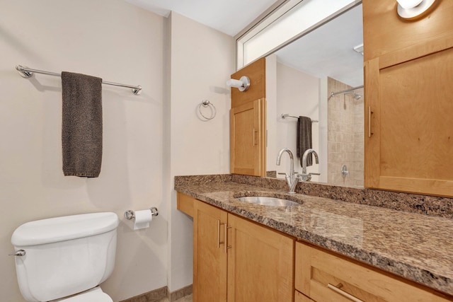 bathroom with vanity, toilet, and tiled shower