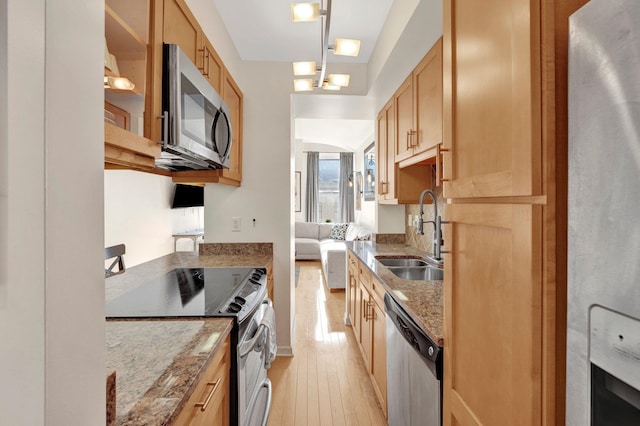 kitchen with stainless steel appliances, sink, stone countertops, light hardwood / wood-style flooring, and hanging light fixtures