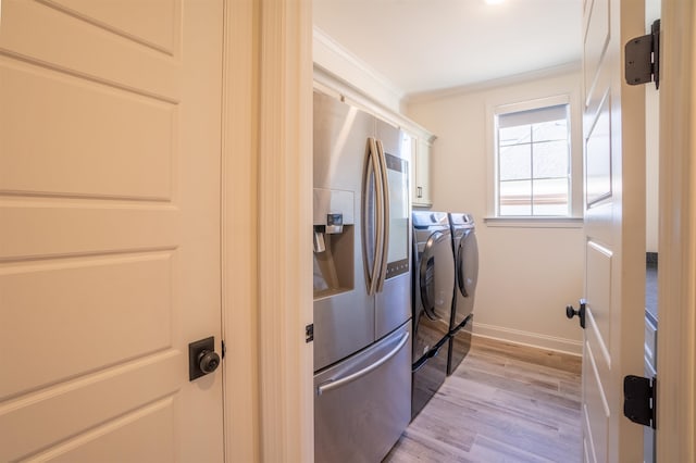 laundry area featuring cabinets, light wood-type flooring, ornamental molding, and washing machine and dryer