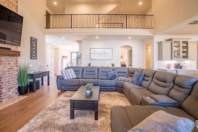 living room featuring a towering ceiling, light hardwood / wood-style floors, and ornamental molding